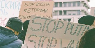 Protest signs at a rally expressing anti-war and anti-Putin sentiments.